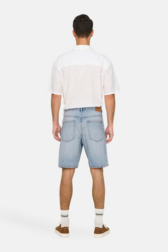 Jean court en denim bleu clair de ONLY & SONS, avec des chaussures brunes et des chaussettes blanches, vu de derrière.