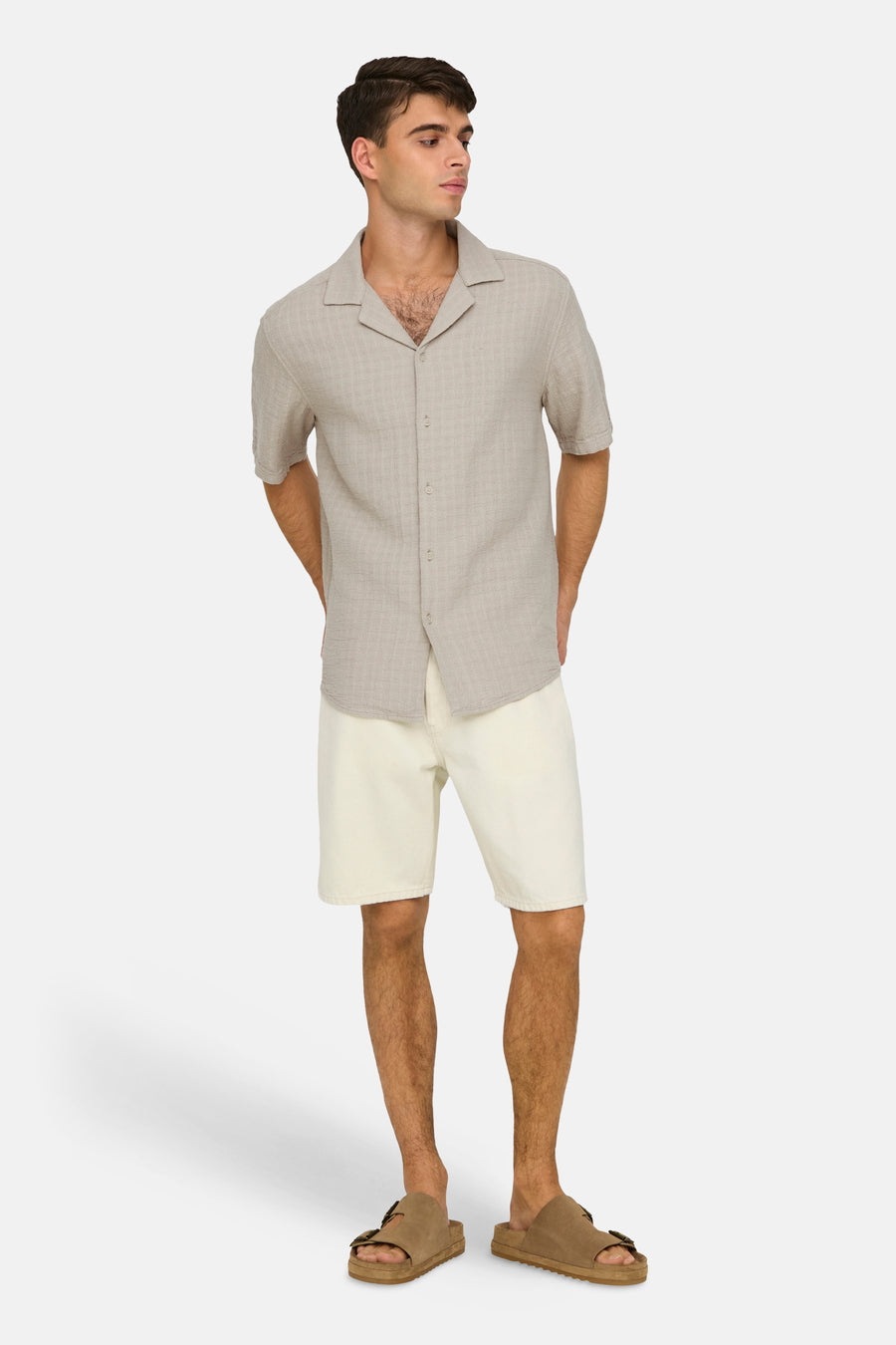 Ecru jeansshort van ONLY & SONS®, gecombineerd met een beige hemd en bruine sandalen.