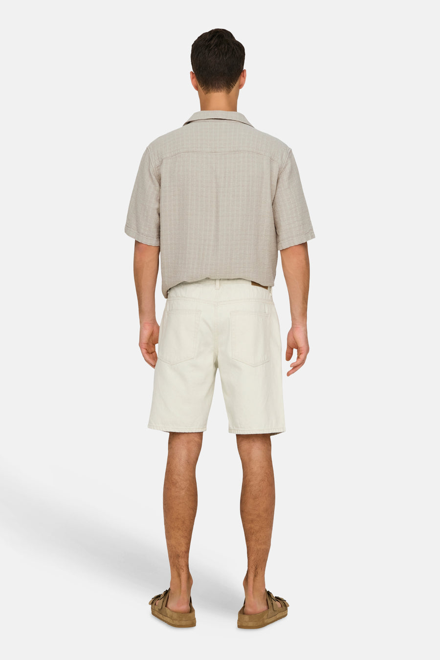 Short en jean écru de ONLY & SONS, vu de dos, combiné avec une chemise beige et des sandales marron.
