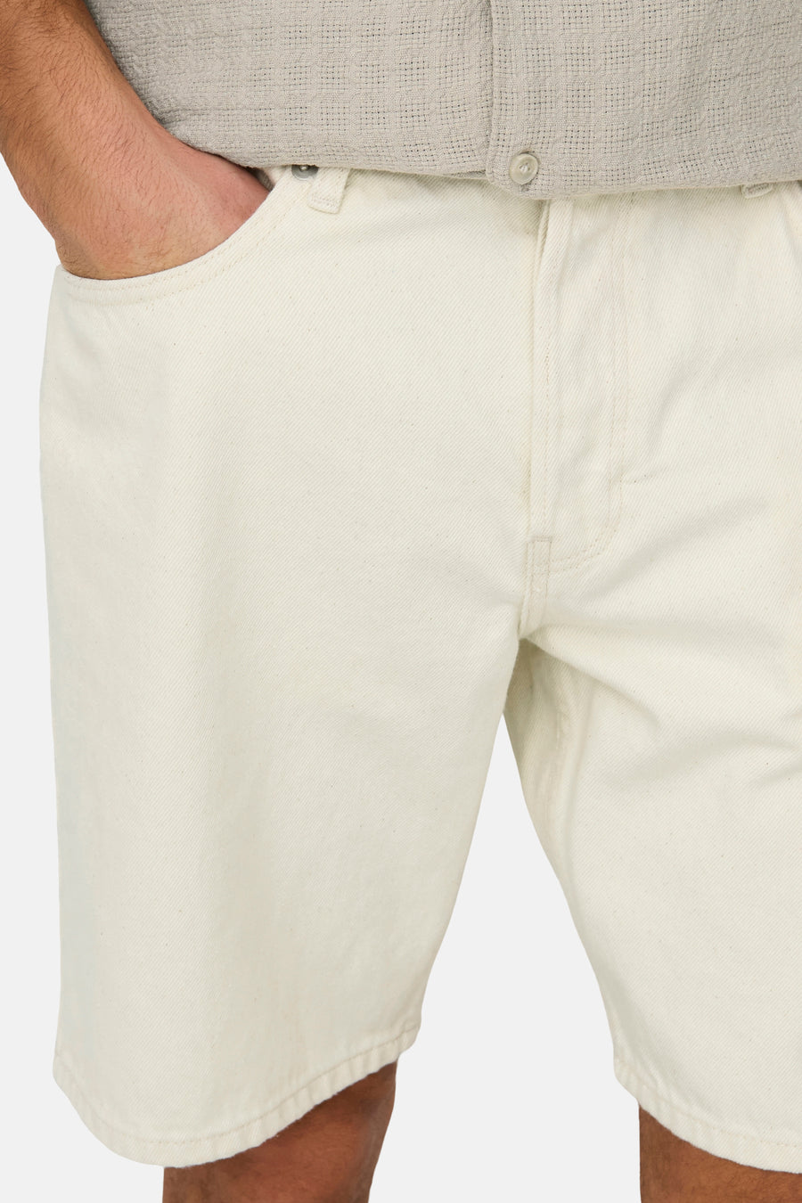 Short en jean écru de ONLY & SONS®, avec poches latérales et coutures subtiles, combiné avec une chemise beige légère.