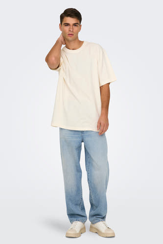 Wijde lichtblauwe denim jeans van ONLY & SONS, met losse pasvorm, gecombineerd met een crèmekleurig t-shirt en bijpassende schoenen.
