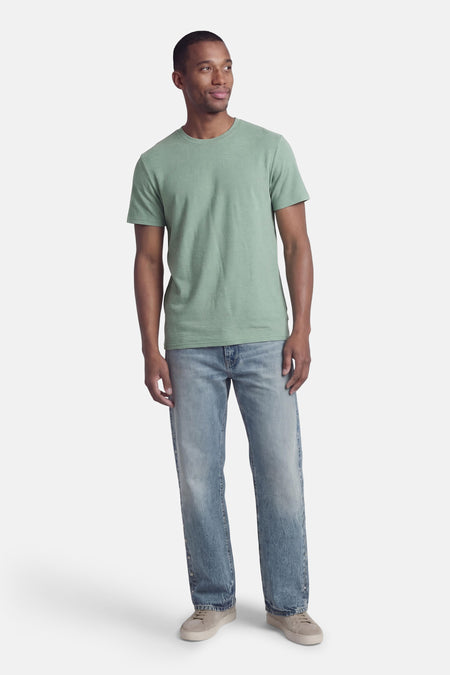 T-shirt vert à manches courtes ONLY & SONS®, porté avec un jean bleu et des chaussures grises.