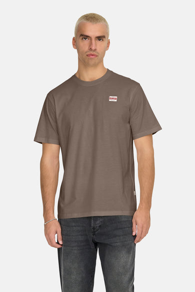 T-shirt brun à manches courtes de ONLY & SONS, avec un col rond et porté avec des jeans noirs.