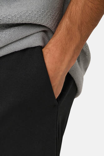 Pantalon noir d'ONLY & SONS avec les mains dans les poches, porté avec un pull gris.