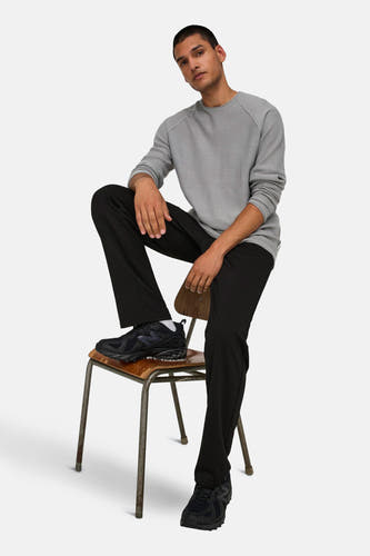 Pantalon noir de ONLY & SONS®, associé à un pull gris et des baskets noires, assis sur une chaise.
