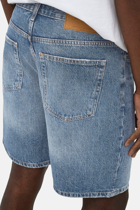 Short en jean de couleur bleu clair moyen de ONLY & SONS, avec poches à l'arrière et patch de marque en cuir, combiné avec un t-shirt blanc.
