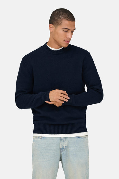 Pull bleu à col rond ONLY & SONS®, à manches longues et détails côtelés, porté avec un t-shirt blanc et un jean.
