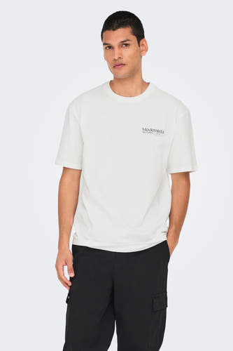 T-shirt blanc à manches courtes de ONLY & SONS®, avec une petite impression, associé à un pantalon noir et des baskets.