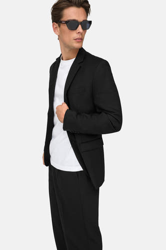 Pantalon noir d'ONLY & SONS, porté avec un t-shirt blanc et une veste noire, avec des lunettes de soleil.