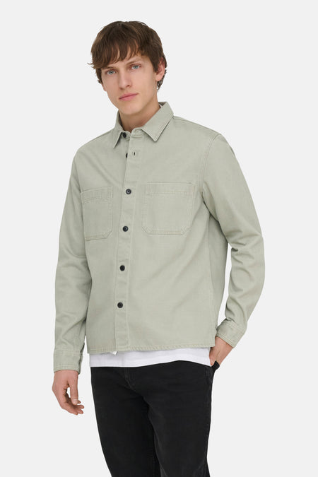 Chemise verte à manches longues ONLY & SONS®, avec poches plaquées et portée sur un t-shirt blanc et un jean noir.