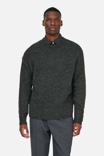 Sweat gris à col rond de ONLY & SONS®, porté sur une chemise rayée et un pantalon gris.