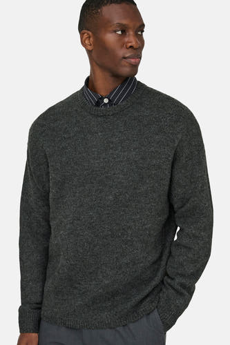 Sweat-shirt gris avec col rond de ONLY & SONS®, porté sur une chemise à rayures, contre un fond uni.