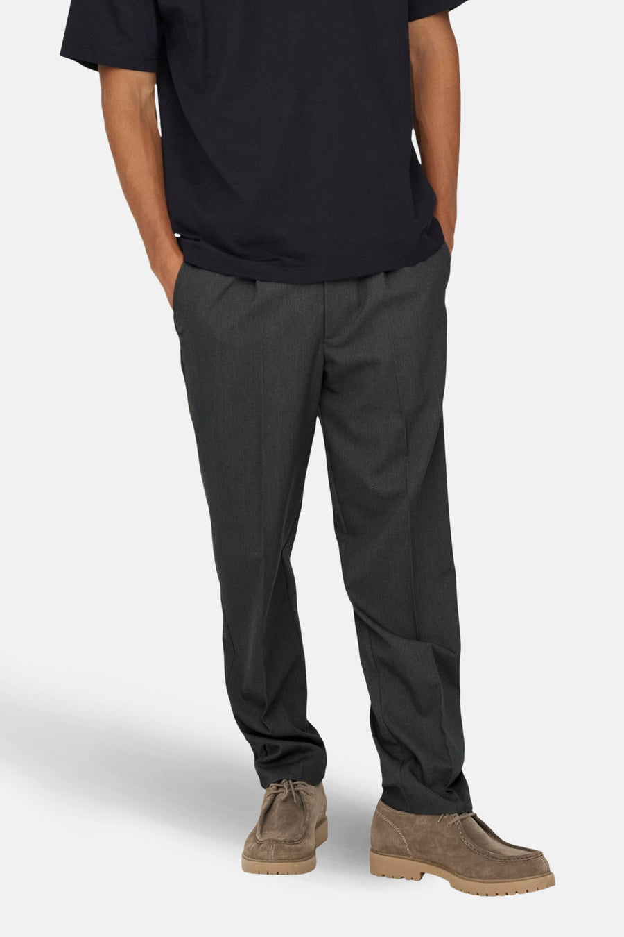 Pantalon gris d'ONLY & SONS®, avec poches et coupe décontractée, associé à des chaussures brunes et un T-shirt noir.