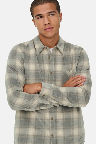 Chemise grise à manches longues d'ONLY & SONS, avec un motif de carreaux et les bras croisés.