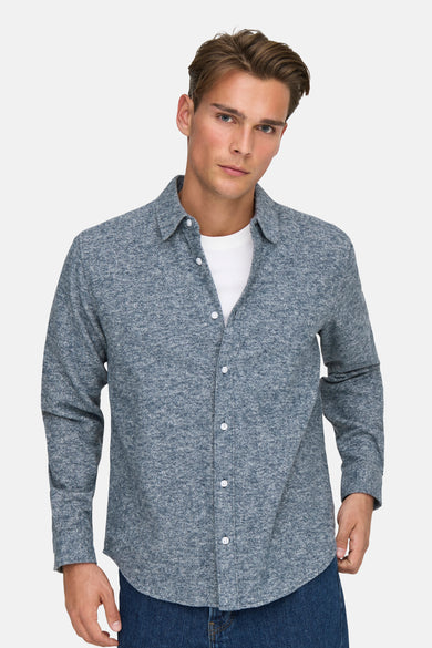 Blauw overhemd met lange mouwen van ONLY & SONS, met witte knopen over een wit T-shirt.
