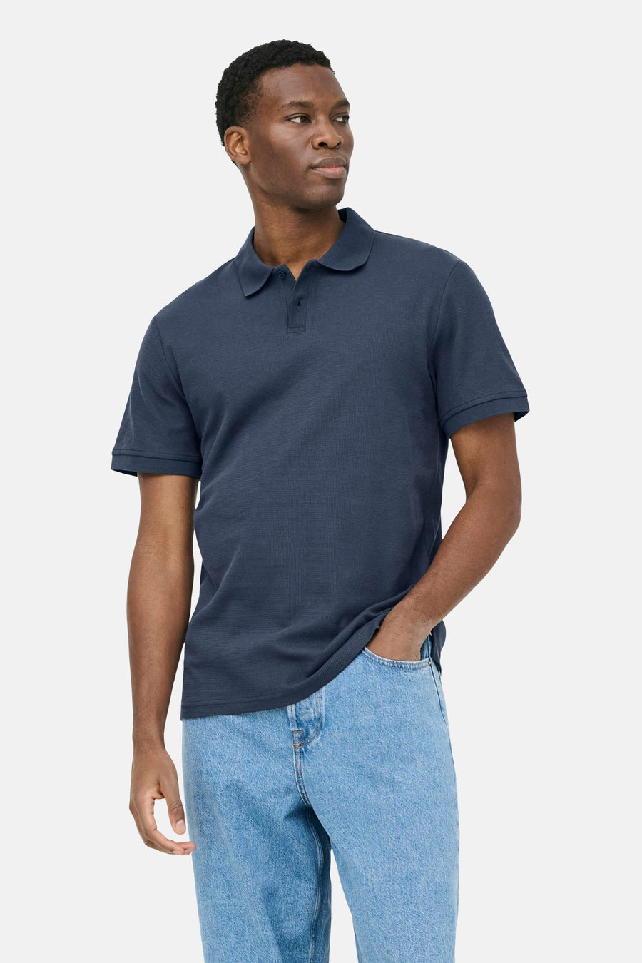 Donkerblauwe korte mouwen polo van ONLY & SONS® met ribstructuur, gedragen door model in lichtblauwe jeans, zijprofiel.