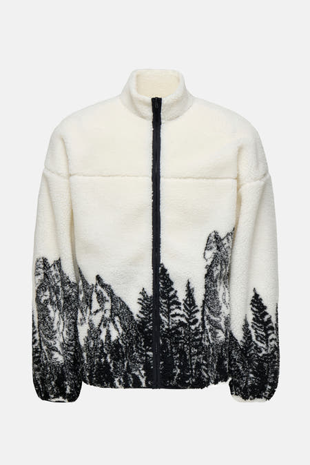 Fausse fourrure blanche d'ONLY & SONS avec des montagnes et des arbres comme éléments décoratifs à l'arrière.