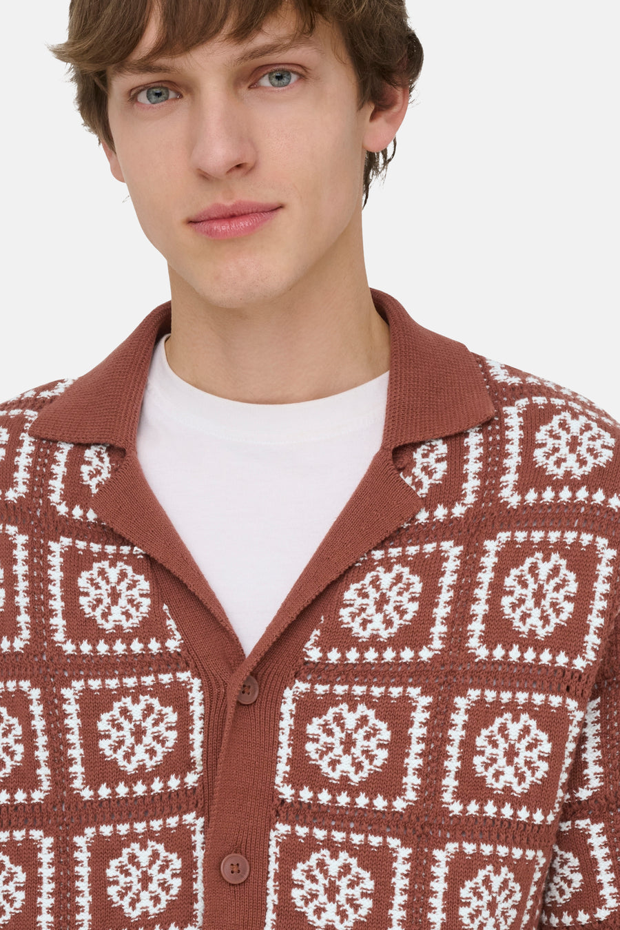 Pull marron ONLY & SONS® avec motifs carrés tricotés blancs et fleurs, avec col à revers, porté sur un t-shirt blanc.