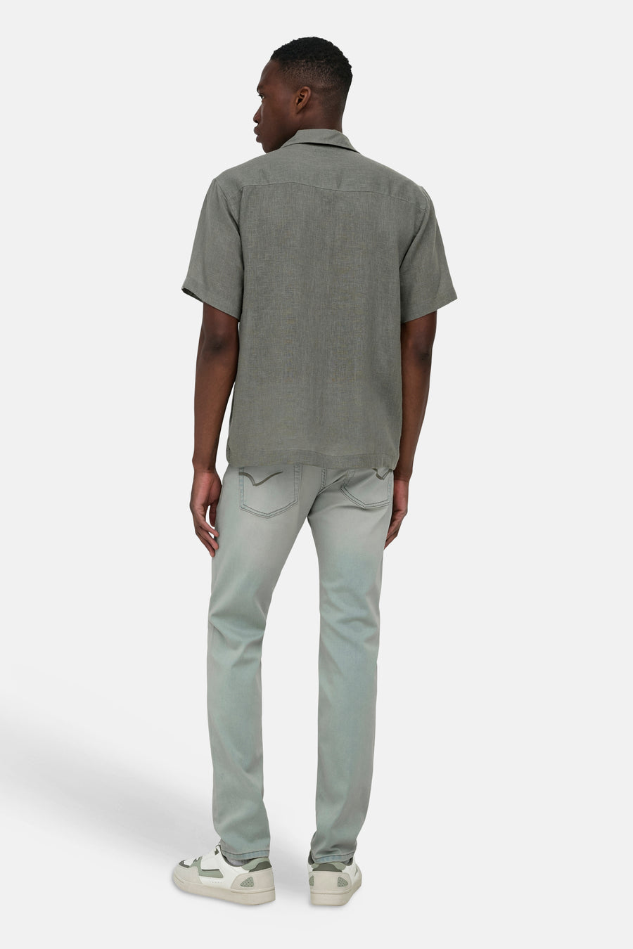Chemise kaki à manches courtes ONLY & SONS®, en tissu texturé, portée par un homme de dos, associée à un jean et des baskets.