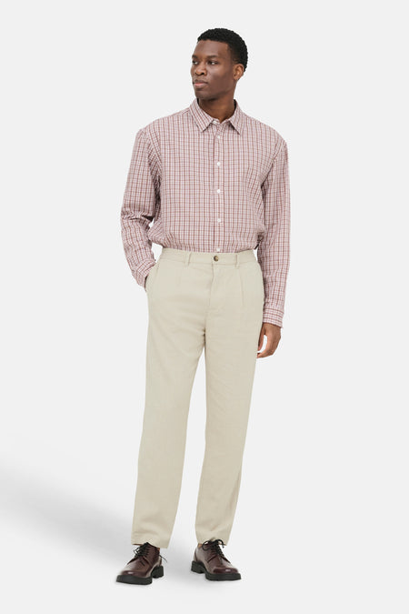 Beige broek van ONLY & SONS® met geplooide voorkant, gedragen door een man met geruit overhemd en bruine schoenen.