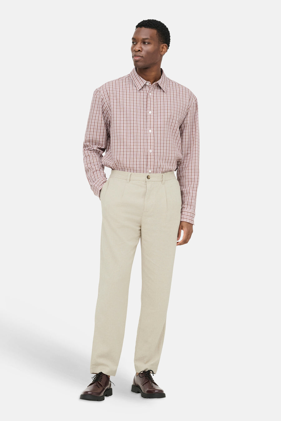 Beige broek van ONLY & SONS® met geplooide voorkant, gedragen door een man met geruit overhemd en bruine schoenen.
