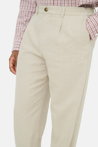 Pantalon beige de ONLY & SONS avec fermeture à boutons, devant plissé et taille élastique, porté avec une chemise à carreaux.
