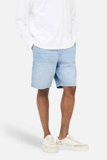 Short en jean bleu clair ONLY & SONS®, combiné avec un t-shirt blanc à manches longues et des baskets de couleur crème.