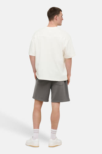 T-shirt blanc à manches courtes ONLY & SONS®, vu de dos, avec short gris et baskets blanches.