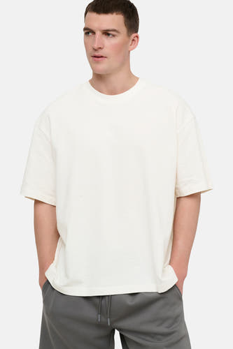 T-shirt blanc à manches courtes ONLY & SONS®, coupe décontractée, porté avec un jogging gris.