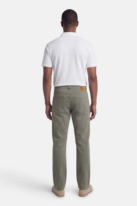 Khaki heren jeans van ONLY & SONS®, met achterzakken, gecombineerd met een wit poloshirt en beige schoenen.
