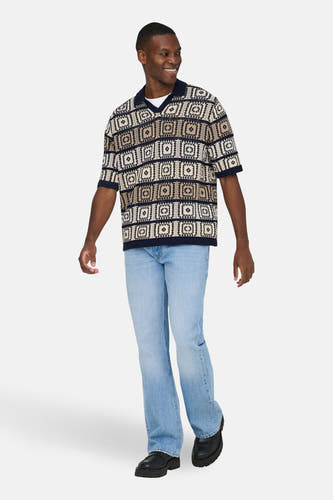 Multikleurige V-hals trui van ONLY & SONS®, met geometrische patronen, gecombineerd met lichtblauwe jeans en zwarte schoenen.