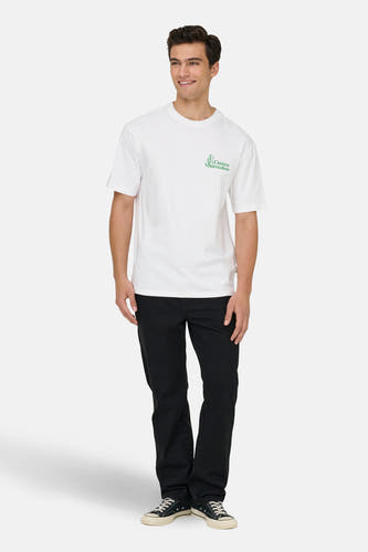 T-shirt blanc à manches courtes de ONLY & SONS®, avec une impression de texte verte et porté avec un pantalon noir et des baskets noires.