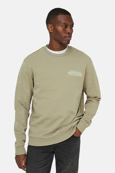 Pull beige à col rond ONLY & SONS, à manches longues et avec un texte imprimé sur le devant, combiné avec une chaîne argentée.