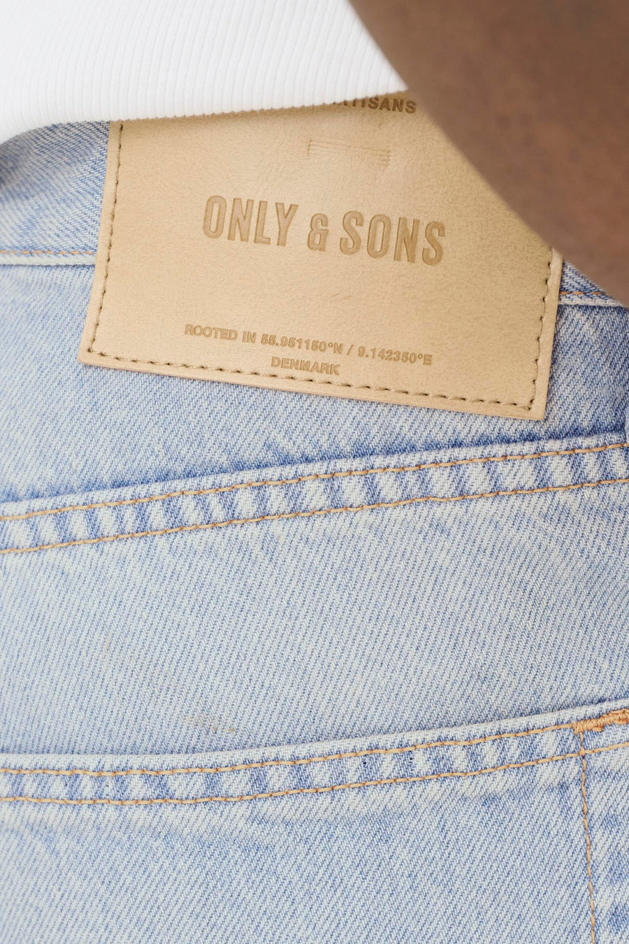 Jean ample bleu clair en denim de ONLY & SONS, avec une étiquette en cuir marron et des surpiqûres orange à l'arrière.