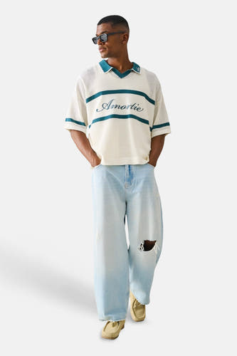 Jean large bleu clair d'ONLY & SONS® avec déchirures, stylé avec un polo crème et des mocassins clairs.