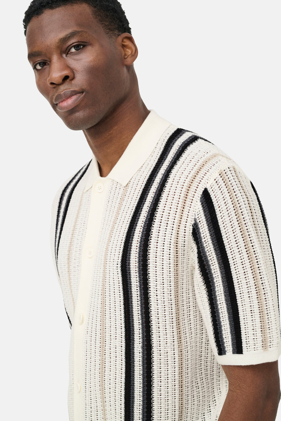 Pull écru ONLY & SONS® avec col polo, texture tricot ouverte, rayures verticales noires et grises et manches courtes, porté par un homme.