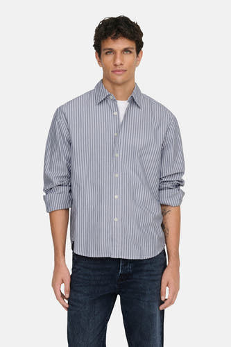 Chemise rayée bleue à longues manches de ONLY & SONS®, avec des manches retroussées, associée à des jeans foncés et des chaussures noires.