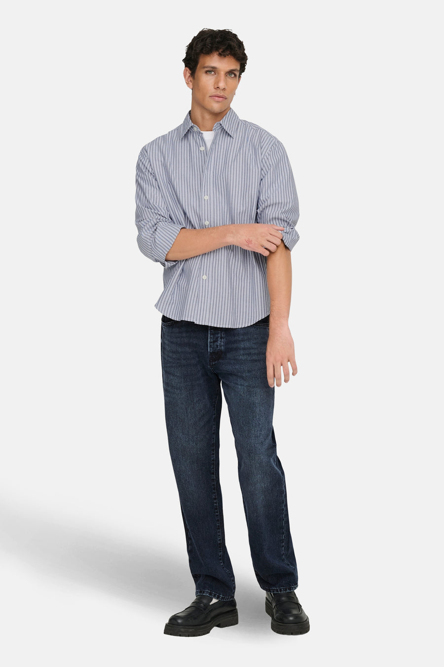 Blauw gestreept overhemd met lange mouwen van ONLY & SONS®, met opgerolde mouwen, gecombineerd met donkere jeans en zwarte schoenen.