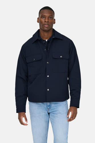 Manteau court bleu de ONLY & SONS, avec des poches devant et porté sur un pull bleu marine et des jeans bleu clair.