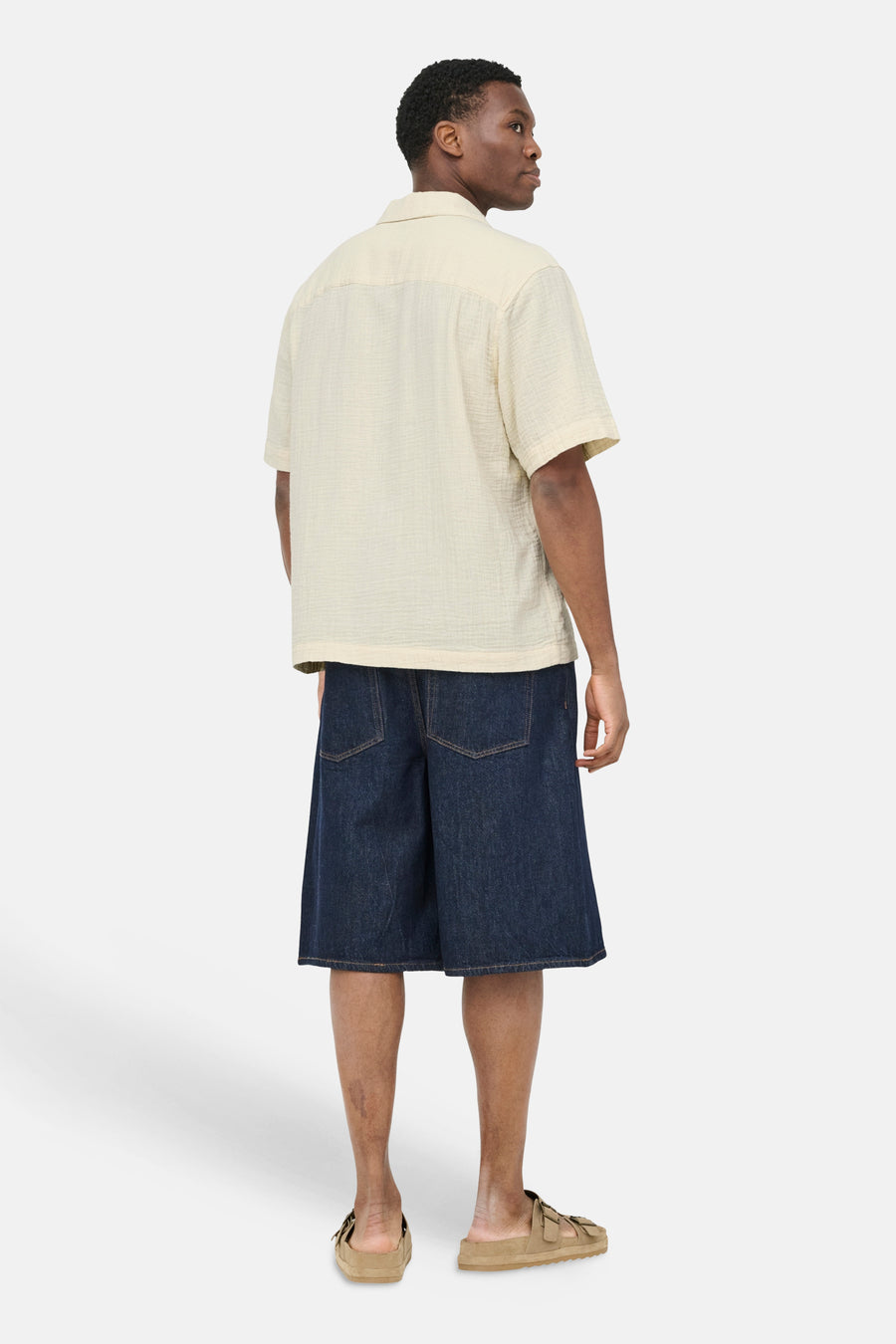 Chemise écru à manches courtes ONLY & SONS® avec texture crêpée, dos visible sur mannequin portant un short en jean bleu foncé et des sandales beiges.