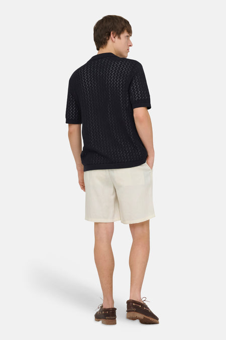 Short écru de ONLY & SONS, combiné avec un polo noir à motif et des chaussures bateau marron.
