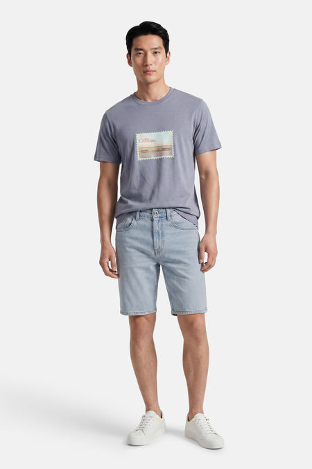 Short en jean bleu clair ONLY & SONS® porté par un homme avec un t-shirt gris avec 'Offline.'baskets blanches à imprimé.