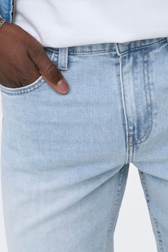 Short en jean en denim bleu clair de ONLY & SONS, avec main dans la poche et délavage subtil.