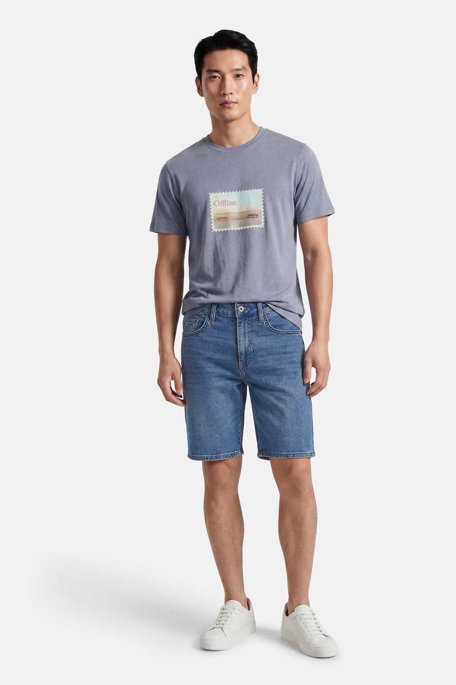 Short en jean bleu moyen de ONLY & SONS®, porté par un homme avec un t-shirt gris et des baskets blanches.