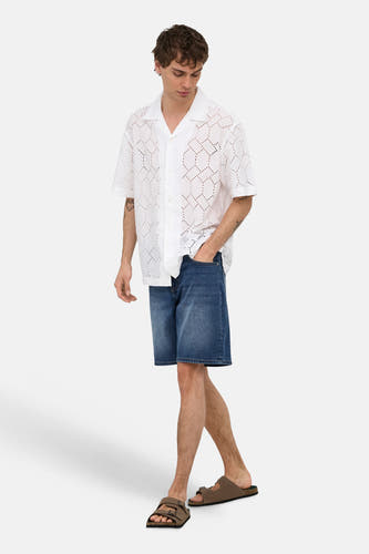 Short en jean de couleur bleu moyen d'ONLY & SONS®, porté par un homme avec une chemise blanche perforée et des sandales marron.