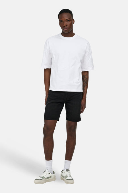 Zwarte jeansshort van denim van ONLY & SONS®, gedragen met een wit T-shirt en witte sokken met sneakers.