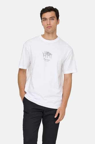 T-shirt blanc à manches courtes ONLY & SONS®, avec un dessin sur le devant, porté avec un pantalon et des chaussures noirs.
