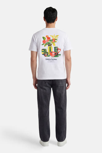 Wit T-shirt met korte mouwen van ONLY & SONS®, met een kleurrijke bloemen en kopjes print op de rug, gedragen met donkere jeans en witte sneakers.
