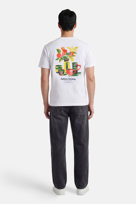 Wit T-shirt met korte mouwen van ONLY & SONS®, met een kleurrijke bloemen en kopjes print op de rug, gedragen met donkere jeans en witte sneakers.
