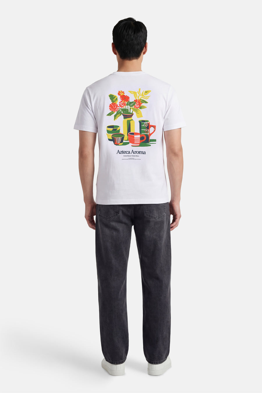 Wit T-shirt met korte mouwen van ONLY & SONS®, met een kleurrijke bloemen en kopjes print op de rug, gedragen met donkere jeans en witte sneakers.
